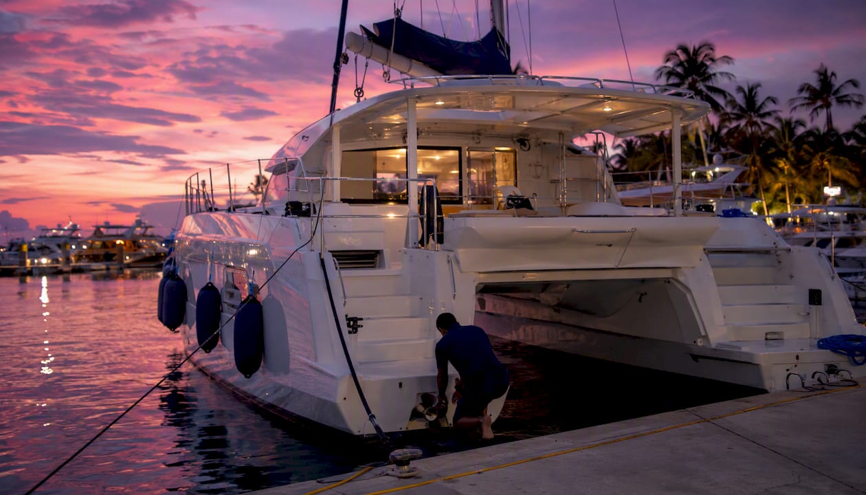 Twin-hulled power catamaran docked at marina golden hour
