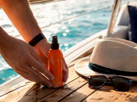 Hands placing insect repellent on yacht deck