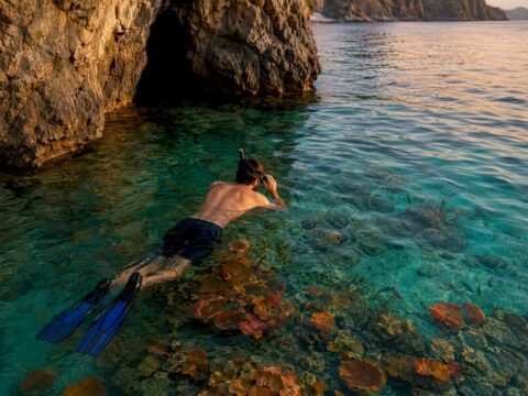 Snorkeler preparing near cave entrance at sunrise