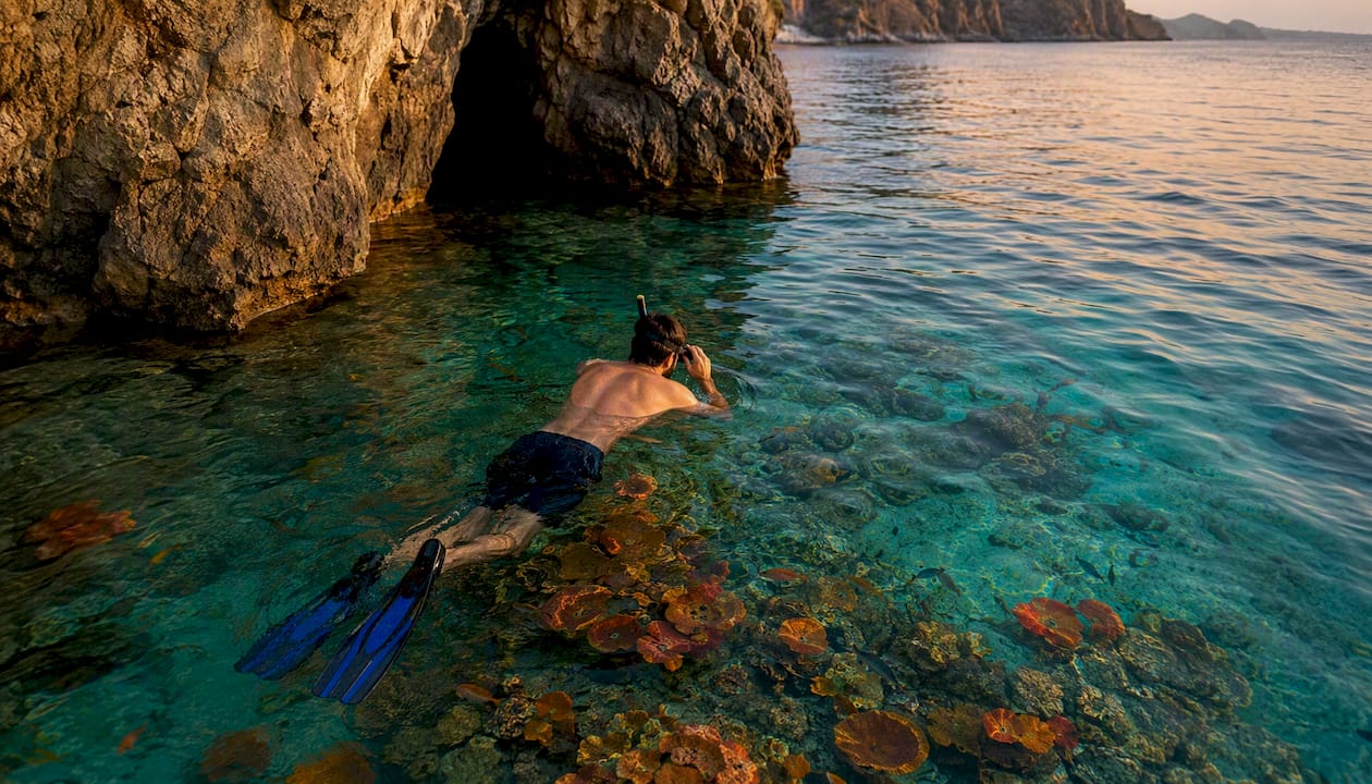 Snorkeler preparing near cave entrance at sunrise