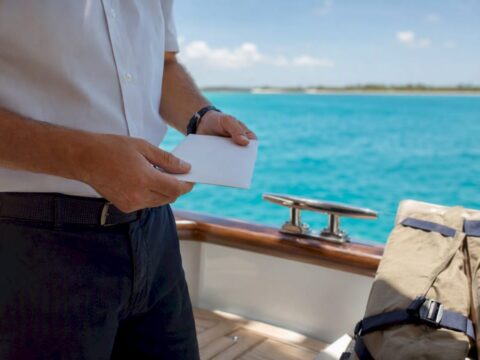 Captain holding tip envelope on yacht deck