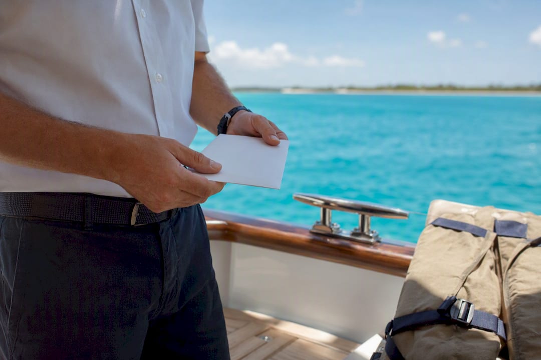 Captain holding tip envelope on yacht deck