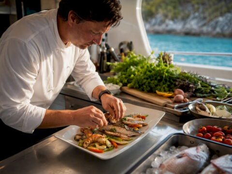 Chef plating gourmet meal in yacht galley
