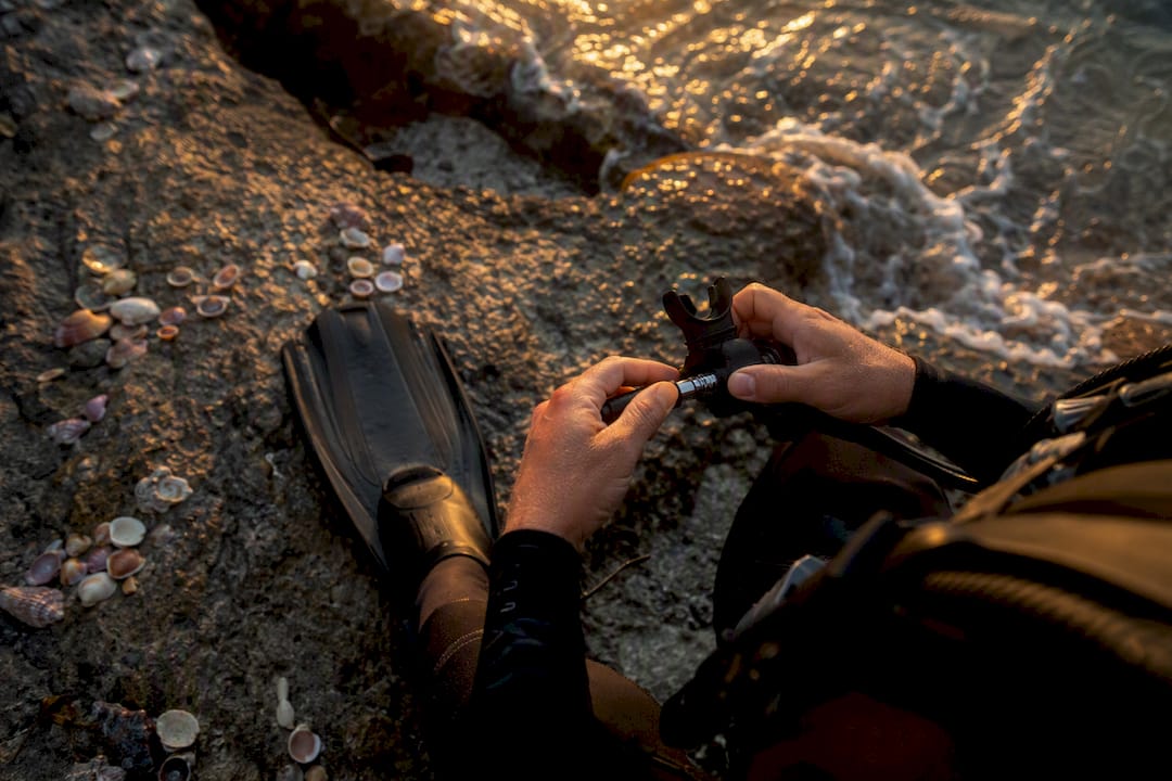 Scuba diver adjusting mask and fins on beach