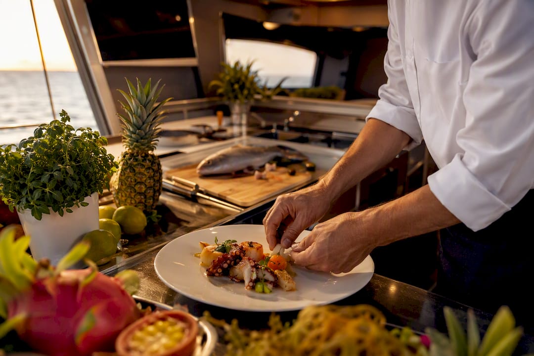 Chef plating fresh seafood dish on yacht galley counter