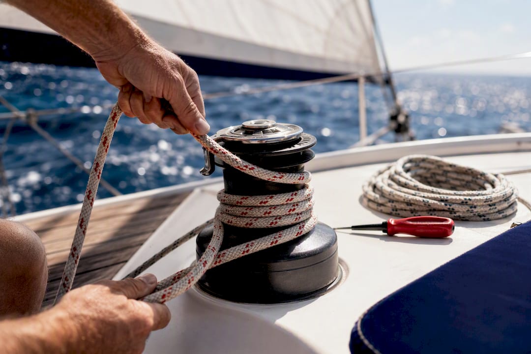 Hands adjusting sail line on open water