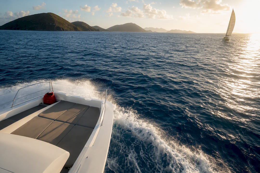 Power wake and distant sail among Caribbean islands